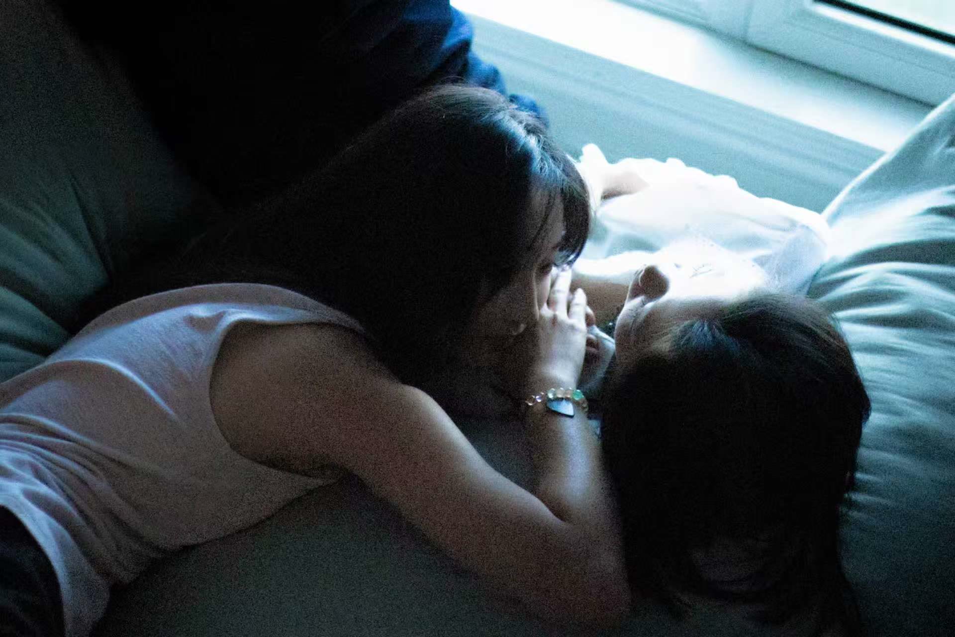 Sapphic couple close together in deep blue interior shadow